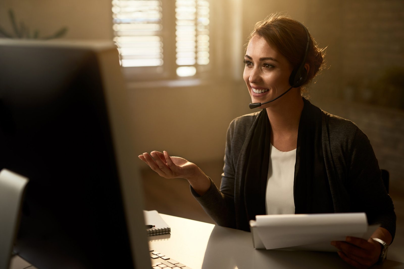 Young happy businesswoman having a video call over desktop PC while working in the office.